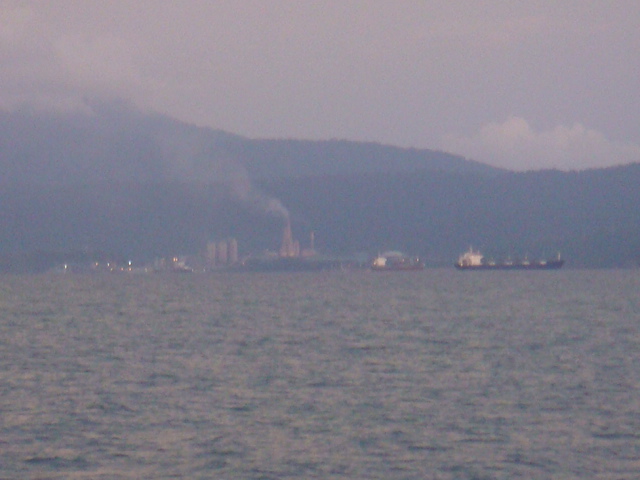 ทางทิศใต้ เห็นโรงงานปูนบนเกาะลังกาวี.....เรือสินค้าใหญ่ๆหลายลำ....