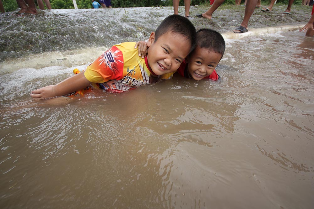 เด็กสองคนนี้สนุกสนานกับการได้เล่นน้ำกลางถนน
 เพราะตั้งแต่เกิดมาก็เพิ่งได้เล่นน้ำกลางถนนเป็นครั้งแรก